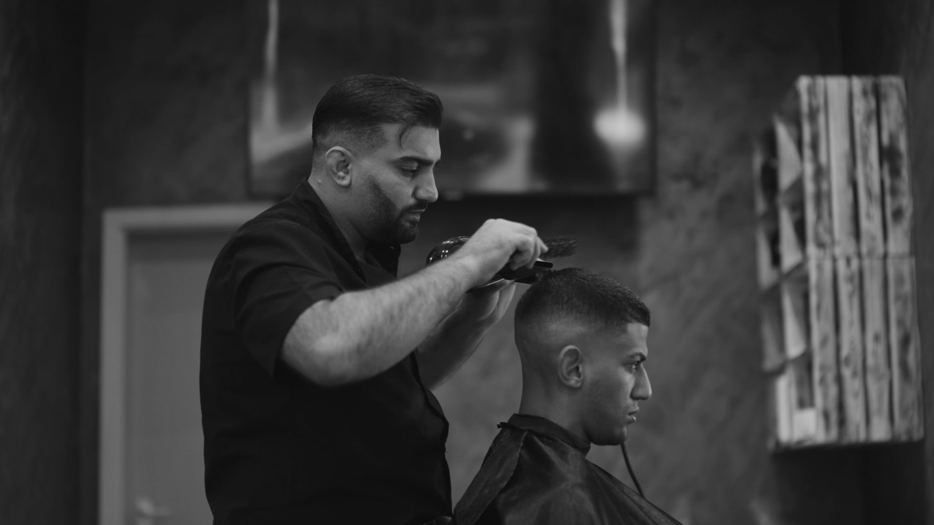 Stylischer Friseur schneidet jungen Mann Haare in modernem Friseursalon. Hautnaher Blick auf die professionelle Haarschneidkunst.